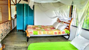 Ein Zimmer mit einem Bett, einem blauen Kleiderschrank und einem Moskitonetz.