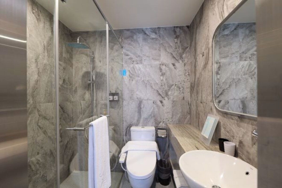 A modern bathroom with a glass-enclosed shower, a white toilet, and a freestanding sink.