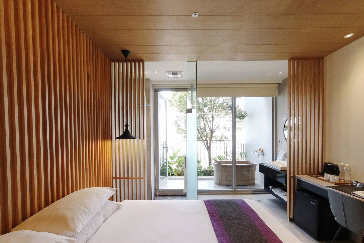 Una habitación de hotel moderna con una cama grande, un escritorio y vistas al exterior.