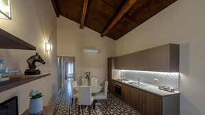 Een moderne keuken met een inbouwfornuis, spoelbak en een decoratieve achterwand. Er is een eethoek met een witte tafel en stoelen, en een gang met een patroon vloer.