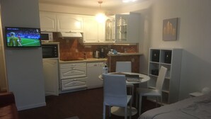 Une chambre d’hôtel compacte comprenant un coin cuisine, un espace repas et un lit.