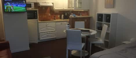 Habitación de hotel compacta con kitchenette, comedor y cama.