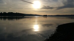 Un lac paisible, sous un ciel dégagé, avec des collines qui se dessinent à l'horizon.