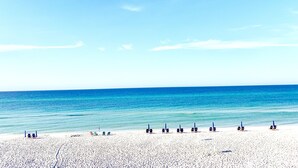 A beach with rows of beach chairs and umbrellas, a clear blue sky, and calm sea. - Steps to 30A & beach with all the comfort of home including a washer & dryer!  (Santa Rosa Beach)