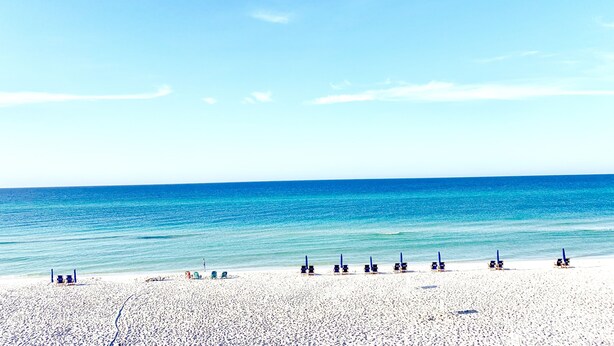 A beach with rows of beach chairs and umbrellas, a clear blue sky, and calm sea. - Steps to 30A & beach with all the comfort of home including a washer & dryer!  (Santa Rosa Beach)