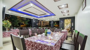 A dining area with tables set for service, featuring a modern ceiling design with recessed lighting and a view of the outdoors. - Hong Chau Hotel (Da Nang)