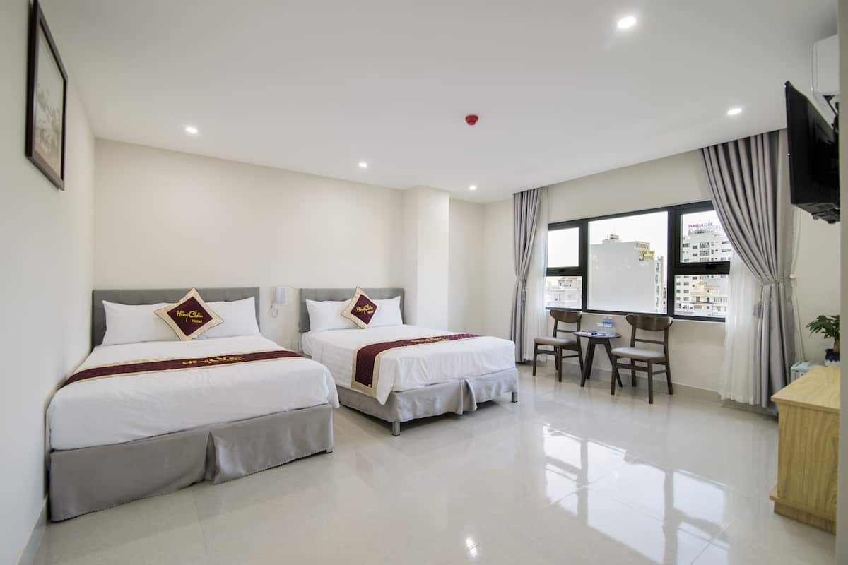 A hotel room with two beds, a desk, and a chair.