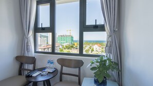 A room with a view of a construction site and buildings. There are two chairs and a table with a plant. - Hong Chau Hotel (Da Nang)