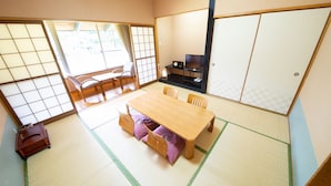 Una stanza tradizionale giapponese con pavimento in tatami, un tavolo di legno basso e un televisore.