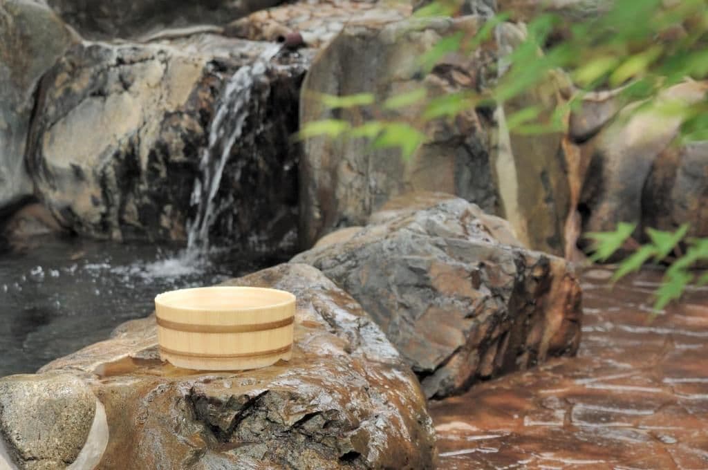 Un cuenco de madera sobre una roca junto a una cascada.