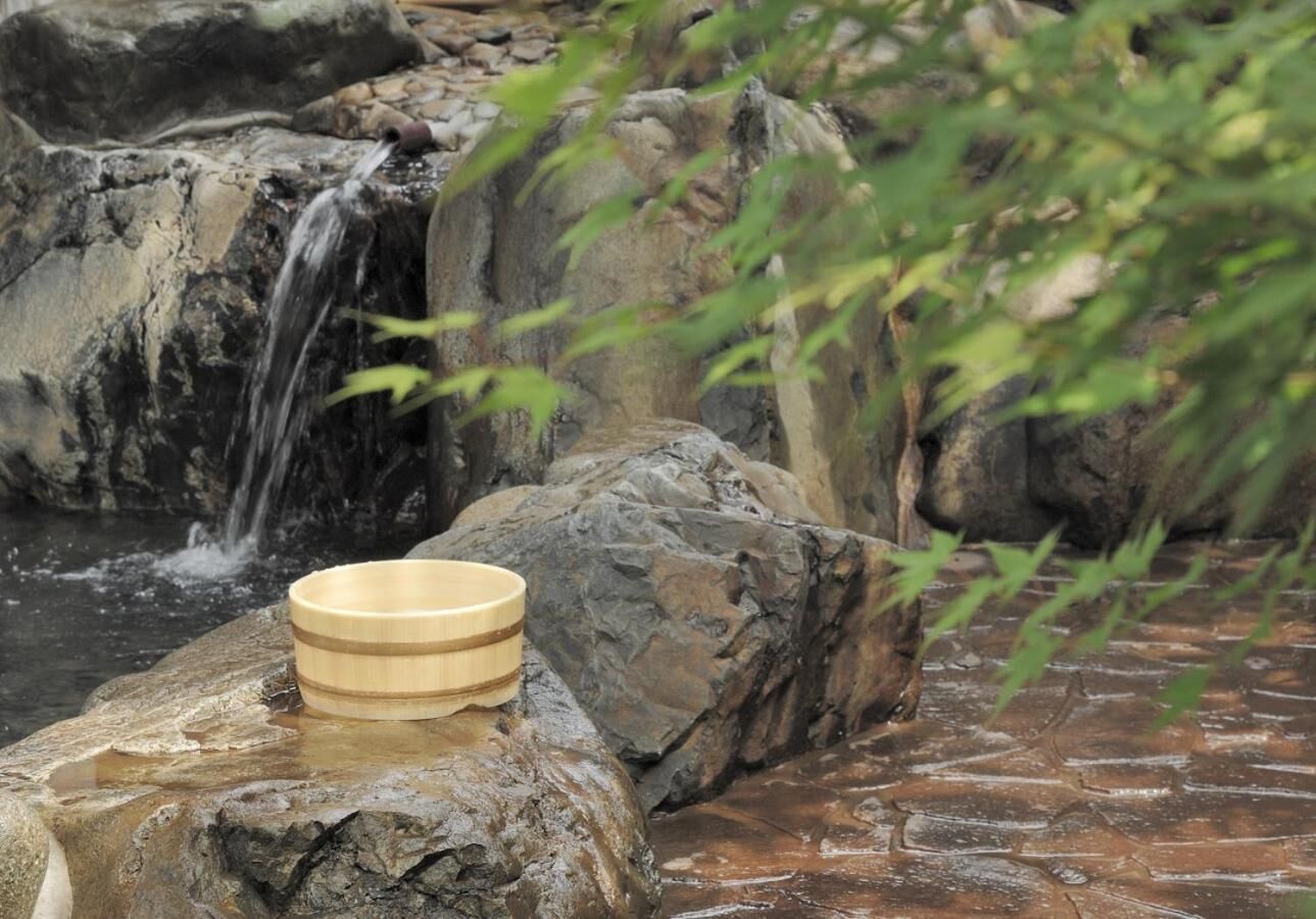 A wooden bowl on a rock by a waterfall.