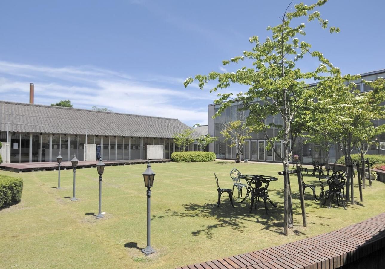 Un patio con césped, mobiliario exterior y un edificio con tejado de baldosas.