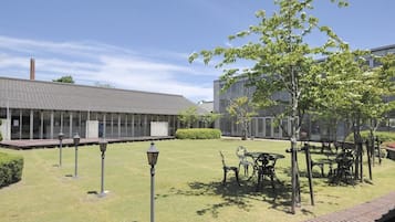 Un patio con césped, mobiliario exterior y un edificio con tejado de baldosas.