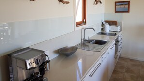 A modern kitchen with a Breville espresso machine, a sink, and a window with a view of the beach. - Stone eco-friendly villa, beachfront acreage. Penguins, koalas (Emu Bay)