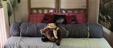 A bedroom with a wooden headboard, a bed with patterned bedding, a stuffed animal, and a sign indicating beach towels are available.