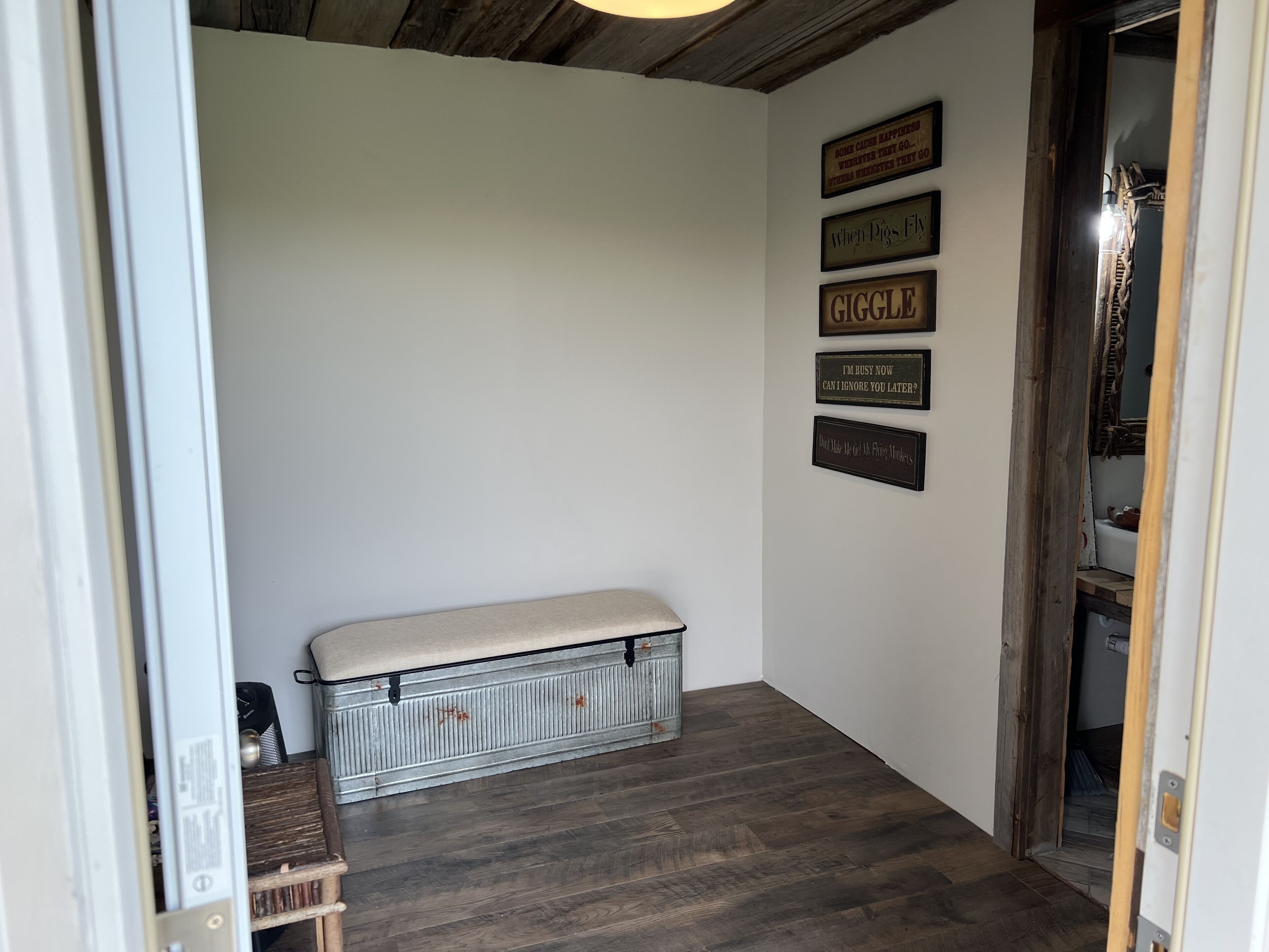 A hallway with a bench, wooden flooring, and wall-mounted signs.