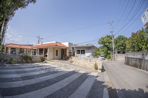 A residential street with houses, a stone wall, and a car parked on the side.