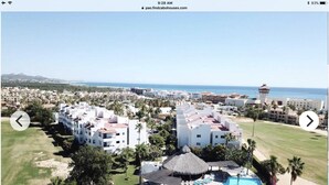 Een resort met een zwembad, meerdere gebouwen en uitzicht op de oceaan.