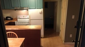 A kitchen with teal cabinets, a wooden dining table, and a patterned rug leading to the door. - Quaint cabin with Lake Pauline views (Ludlow)