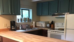 A kitchen with teal cabinets, a wooden countertop, a white stove, and a microwave. - Quaint cabin with Lake Pauline views (Ludlow)