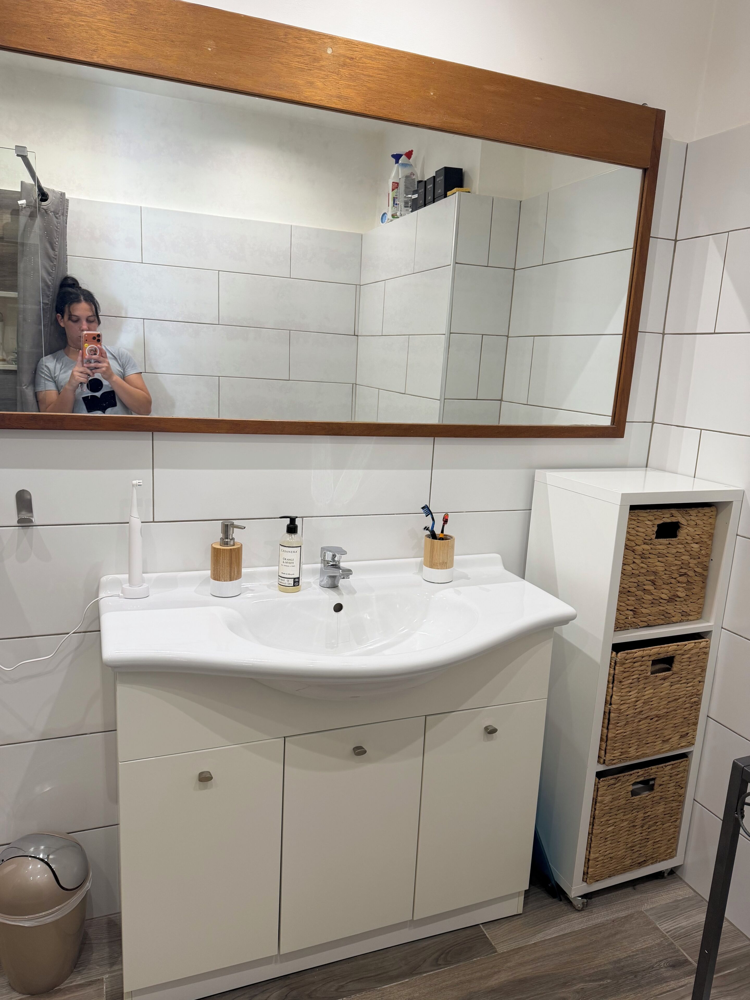 A bathroom with a white sink, mirror, and cabinets.