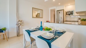Un comedor moderno con una mesa blanca dispuesta para cuatro personas, una camino de mesa azul y un espejo en la pared.