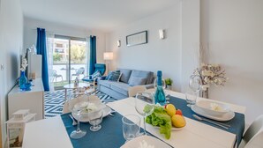 Una sala de estar moderna con comedor, que incluye un sofá, una mesa de comedor con platos, vasos y una botella de champán.