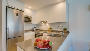 Una cocina moderna con electrodomésticos de acero inoxidable, un microondas integrado y un tazón de fruta sobre la encimera.