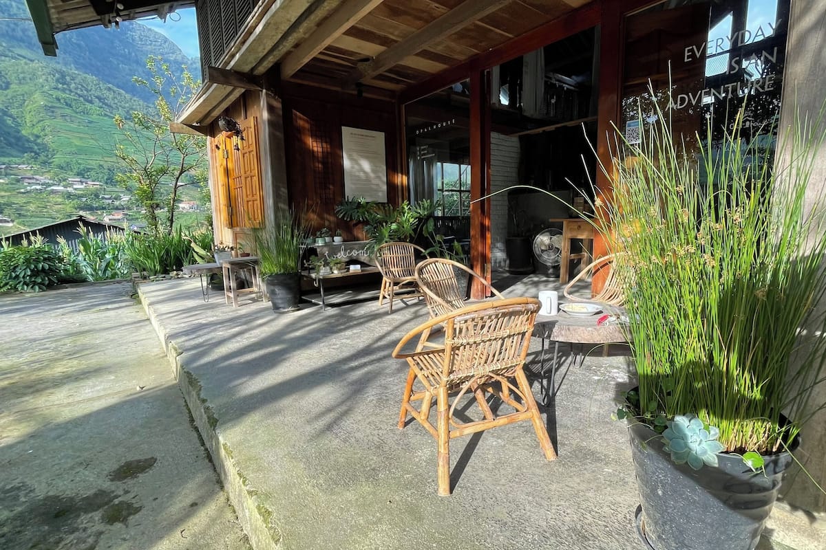A wooden building with a porch, outdoor seating, and potted plants.