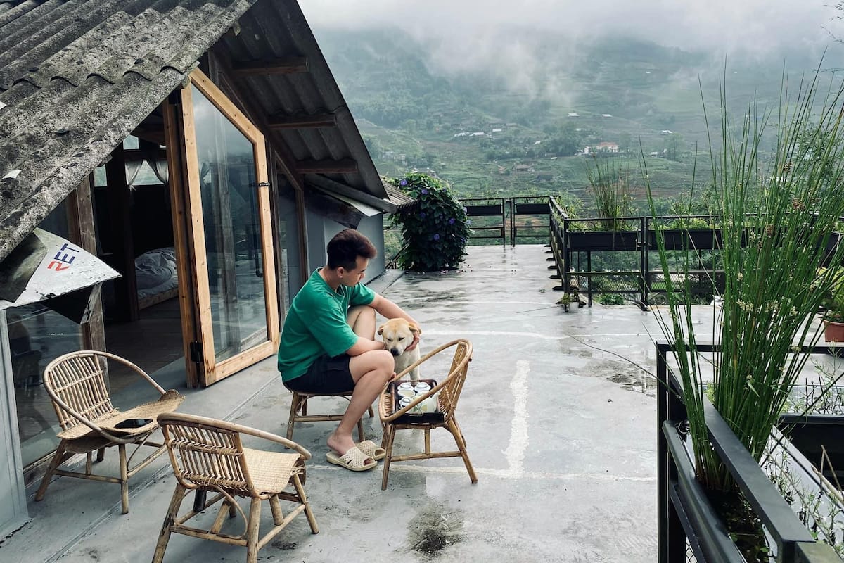 A person sitting on a chair outside a building with a view of a valley.