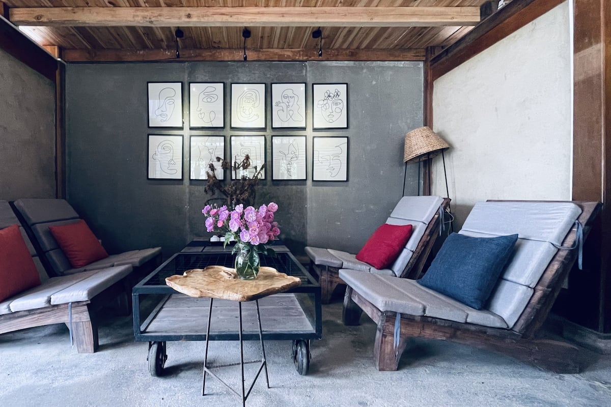A lounge area with two cushioned chairs, a small table with a vase of flowers, and a wall with framed artwork.