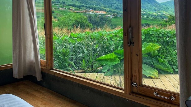 A room with a large window offering a view of a mountainous landscape. - Opal house (Ta Van)