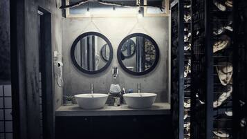 A bathroom with two sinks, each with a round mirror above. There is a telephone and a small plant on the counter.