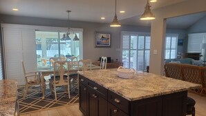 Una cuina amb armaris foscos, un taulell de granat i una illa gran.