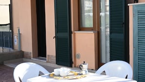 A table set with white chairs, a coffee pot, and a tray with cups and saucers outside a building with green shutters. - S100 - Sirolo, new three-room apartment with terrace (Sirolo)