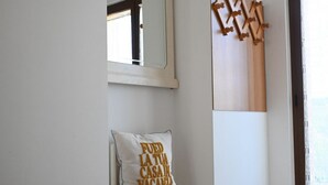 A hotel room with a bed, a chair with a cushion, a mirror, and a window with a curtain. - S100 - Sirolo, new three-room apartment with terrace (Sirolo)