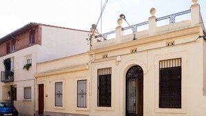 A building with a beige facade, black window bars, and a balcony with potted plants. - Terraced house at the beach. Barcelona. Free Wifi (Canet de Mar)