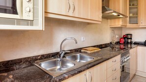 A modern kitchen with a double sink, stainless steel appliances, and wooden cabinets. - Terraced house at the beach. Barcelona. Free Wifi (Canet de Mar)