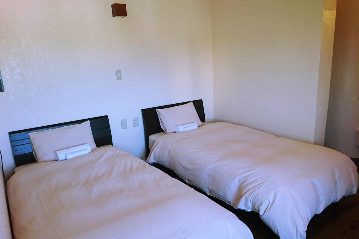 Two single beds with wooden headboards in a room with white walls and a small light fixture above the beds.