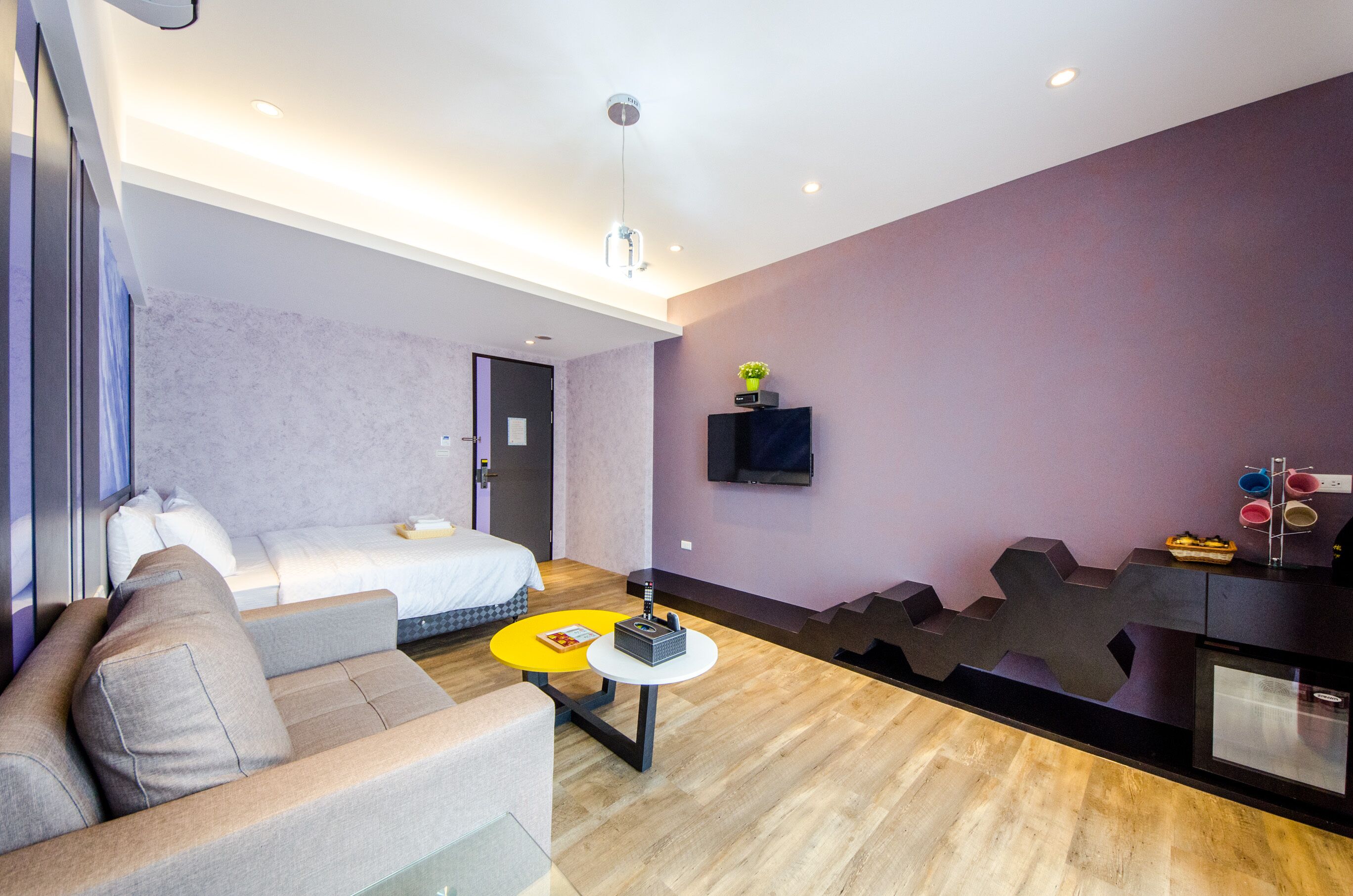 Una habitación de hotel moderna con una cama, sofá y una mesita con un control remoto.