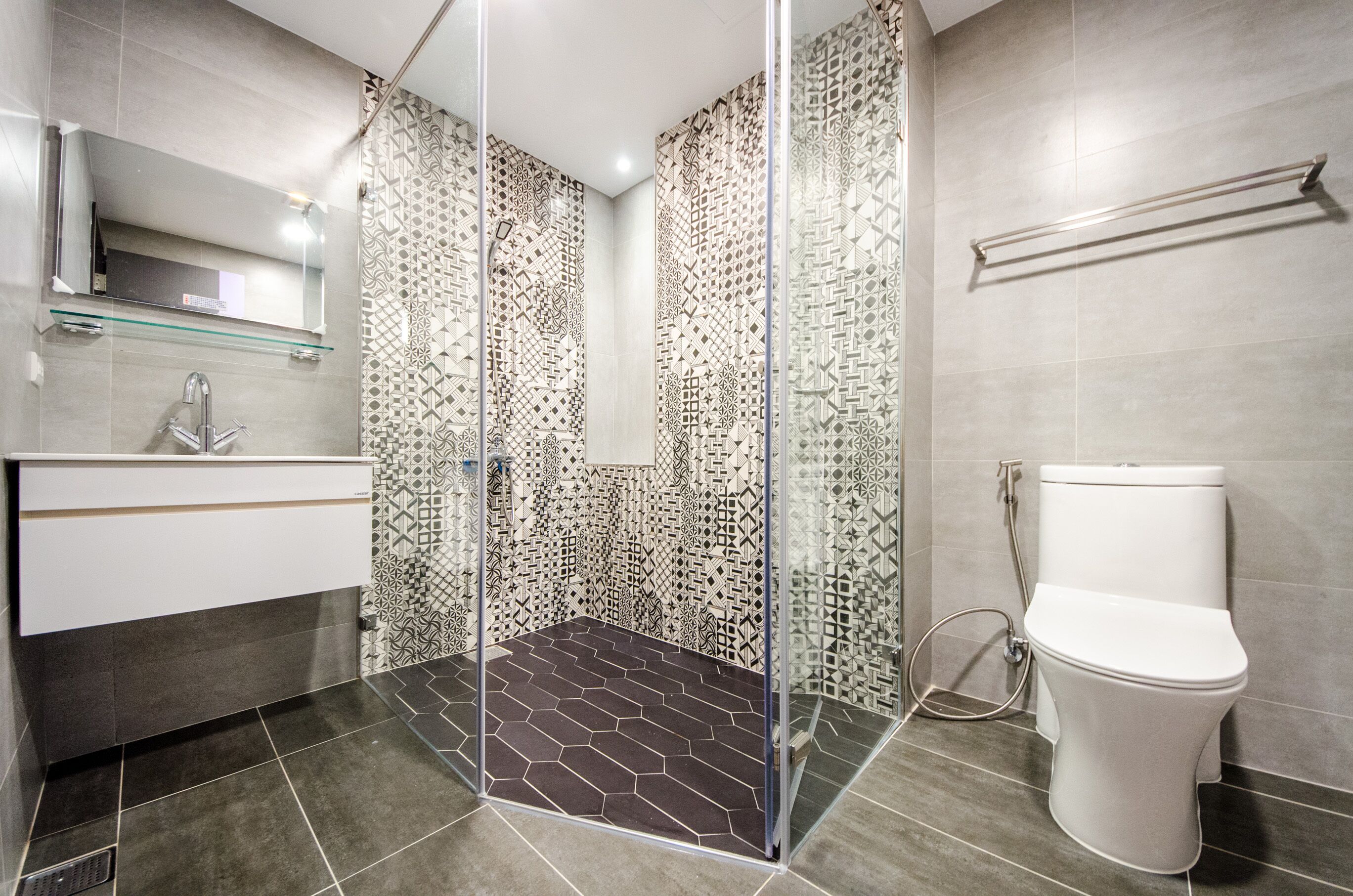 A modern bathroom with a glass shower enclosure, a white toilet, and a vanity with a mirror.