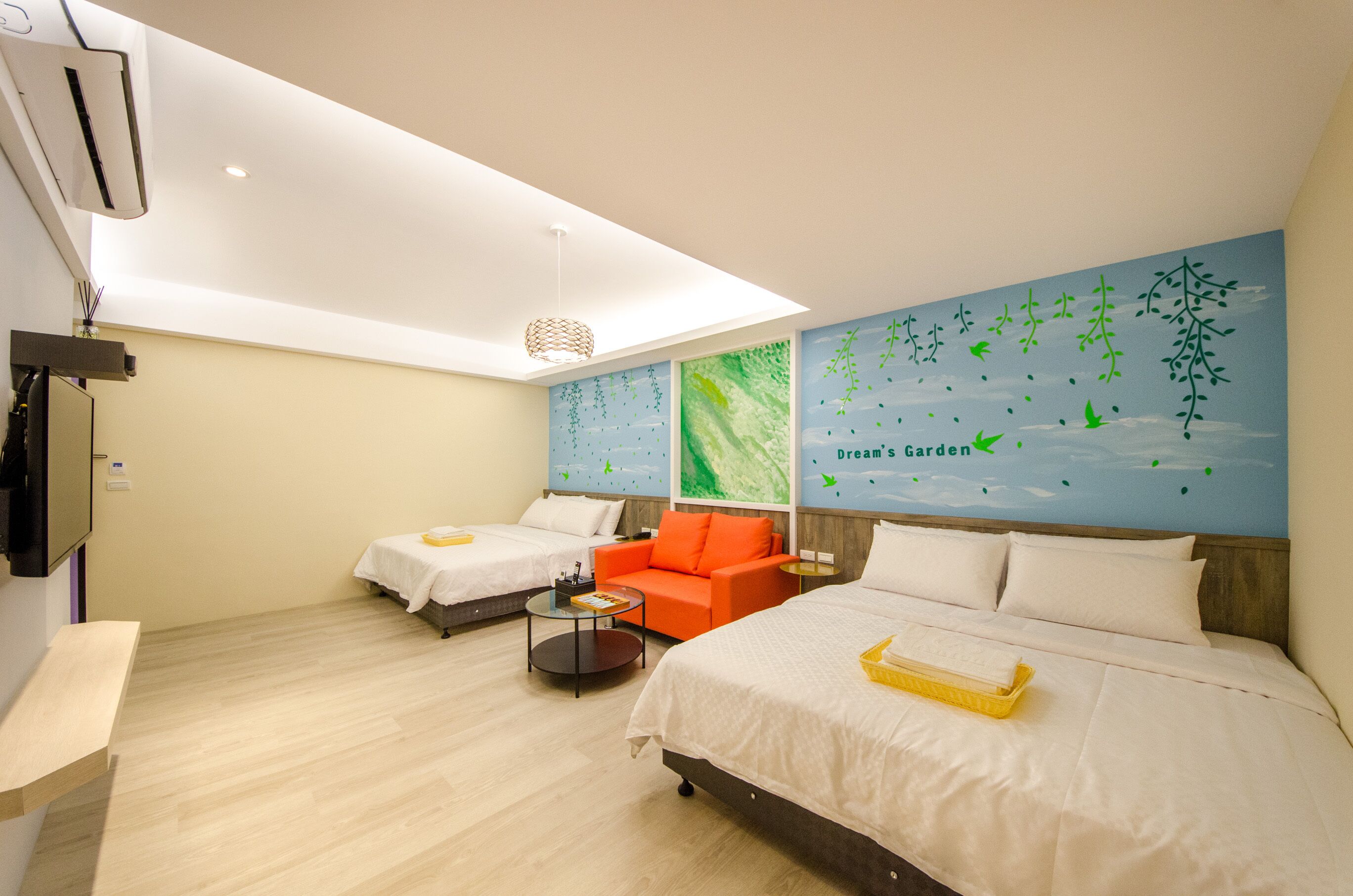A hotel room with two beds, a sofa, a small table, and a wall mural.