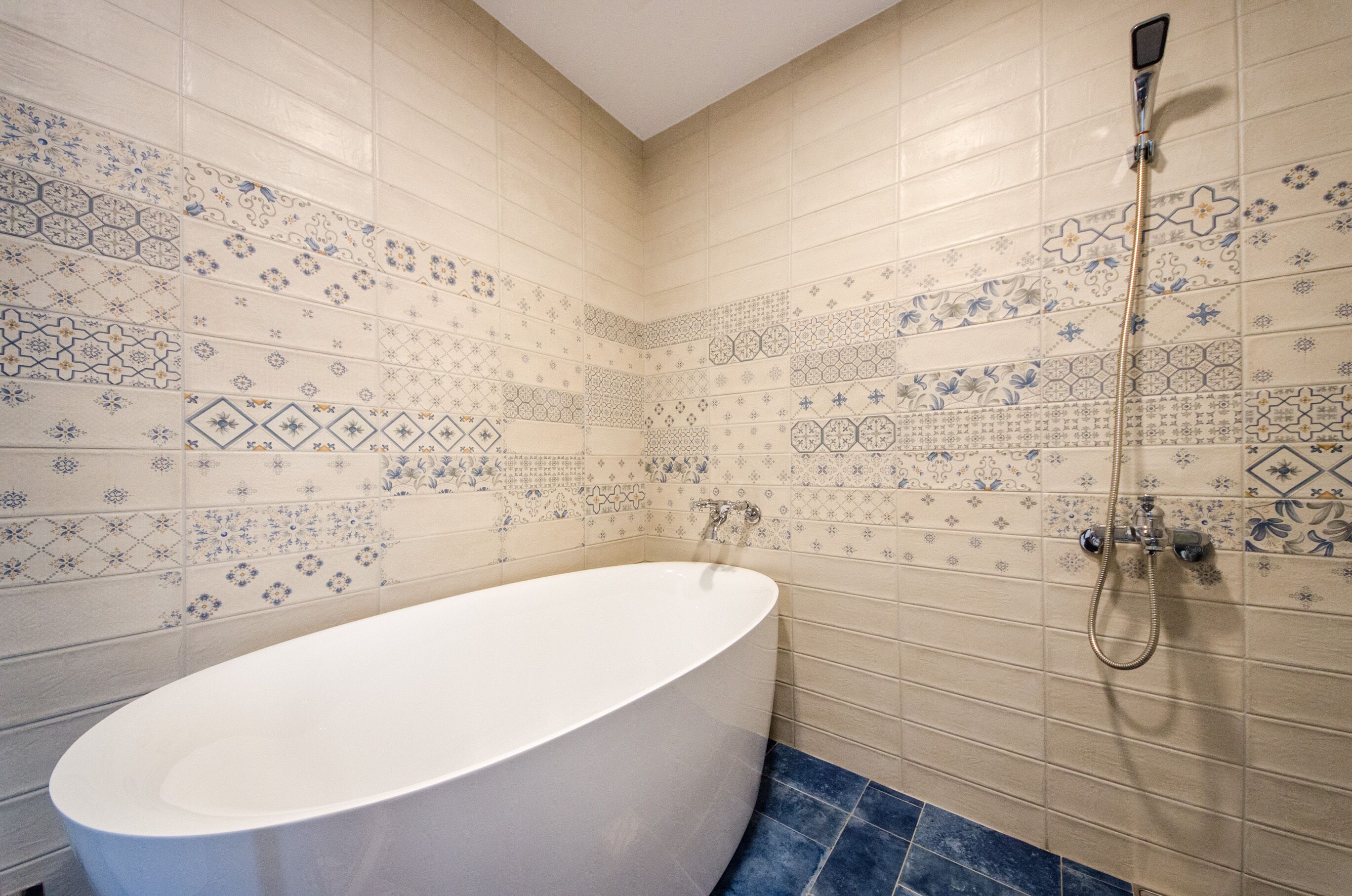 A bathroom with a freestanding bathtub, a shower, and decorative tiles.