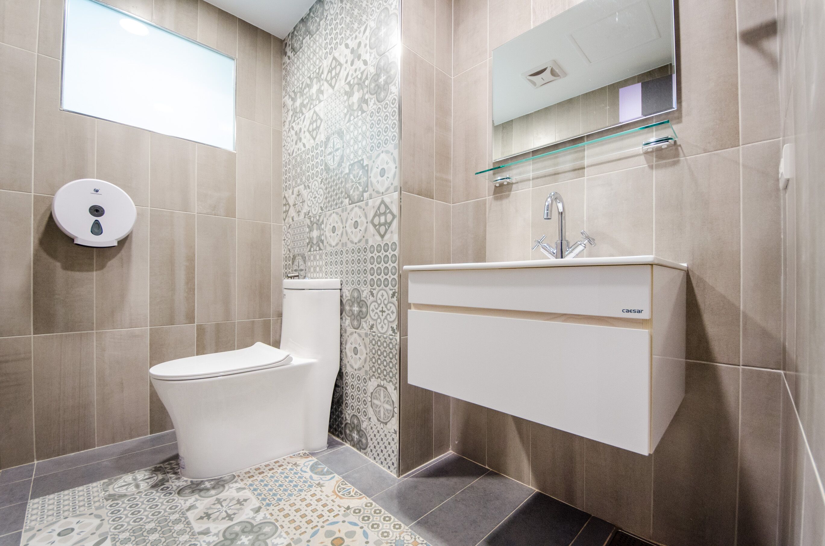 Un baño moderno con inodoro, lavamanos y pared con diseño.