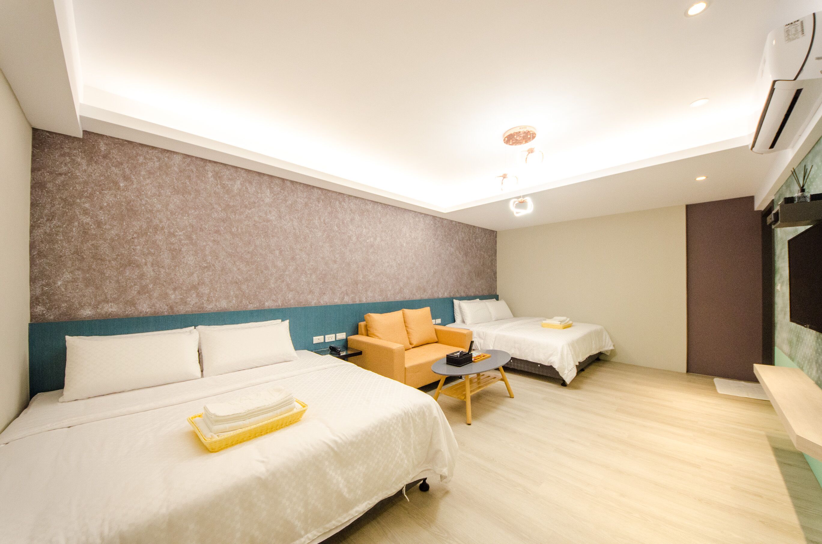 Une chambre d’hôtel avec deux lits, un canapé, une petite table et un appareil de climatisation.