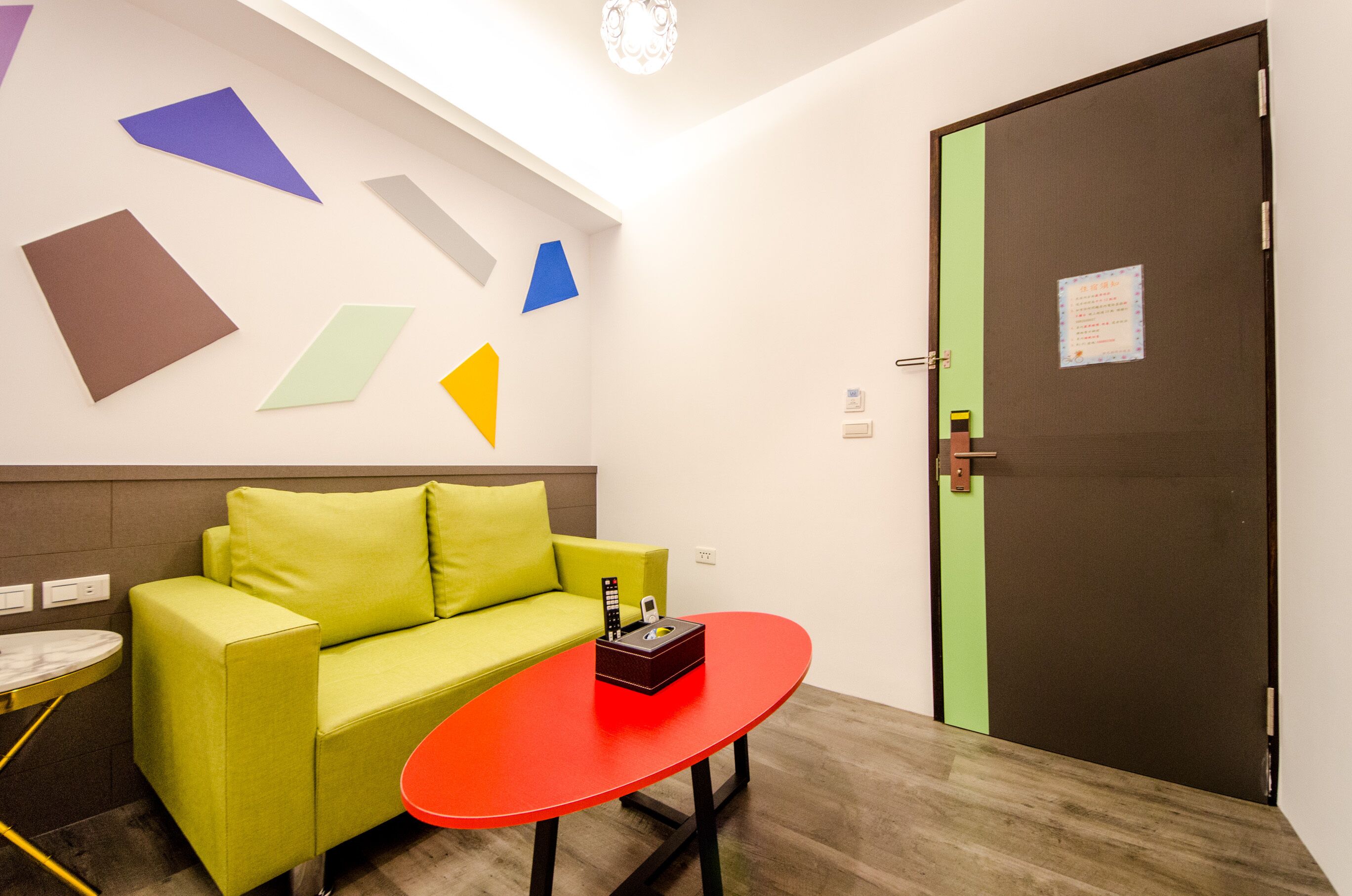A modern room with a green sofa, a red table, and geometric wall art.