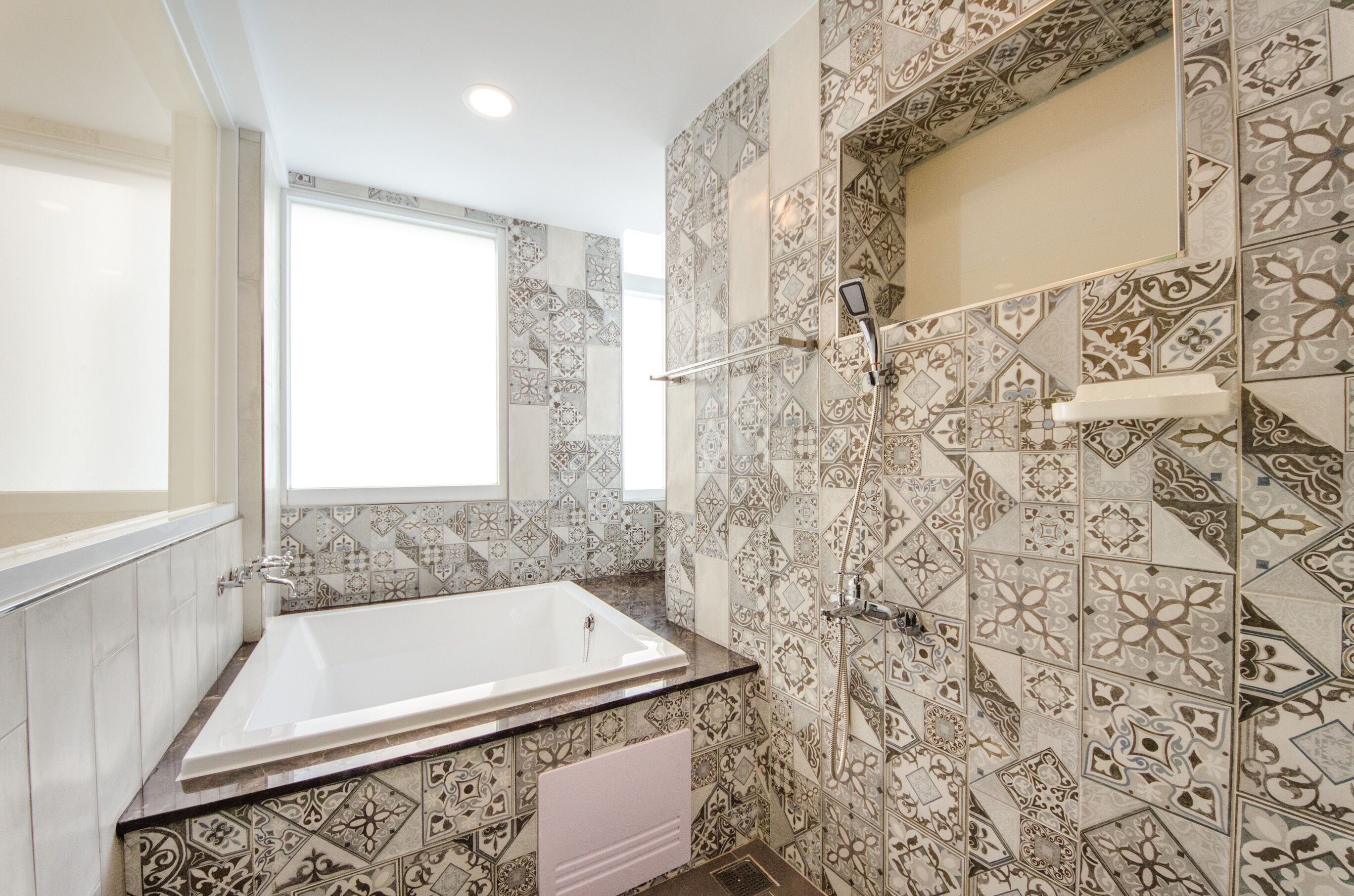 A bathroom with a large bathtub, a shower, and patterned tiles.