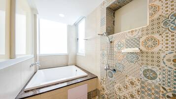 A modern bathroom with a bathtub, shower, and patterned tiles.