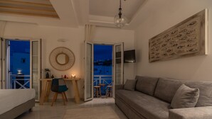 A modern living room with a sofa, a desk, and a dining area. - Central suites (Mykonos)