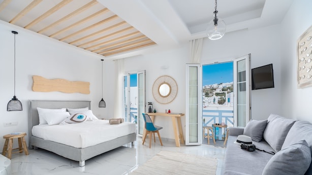 A modern bedroom with a bed, a desk, and a sofa. - Central suites (Mykonos)